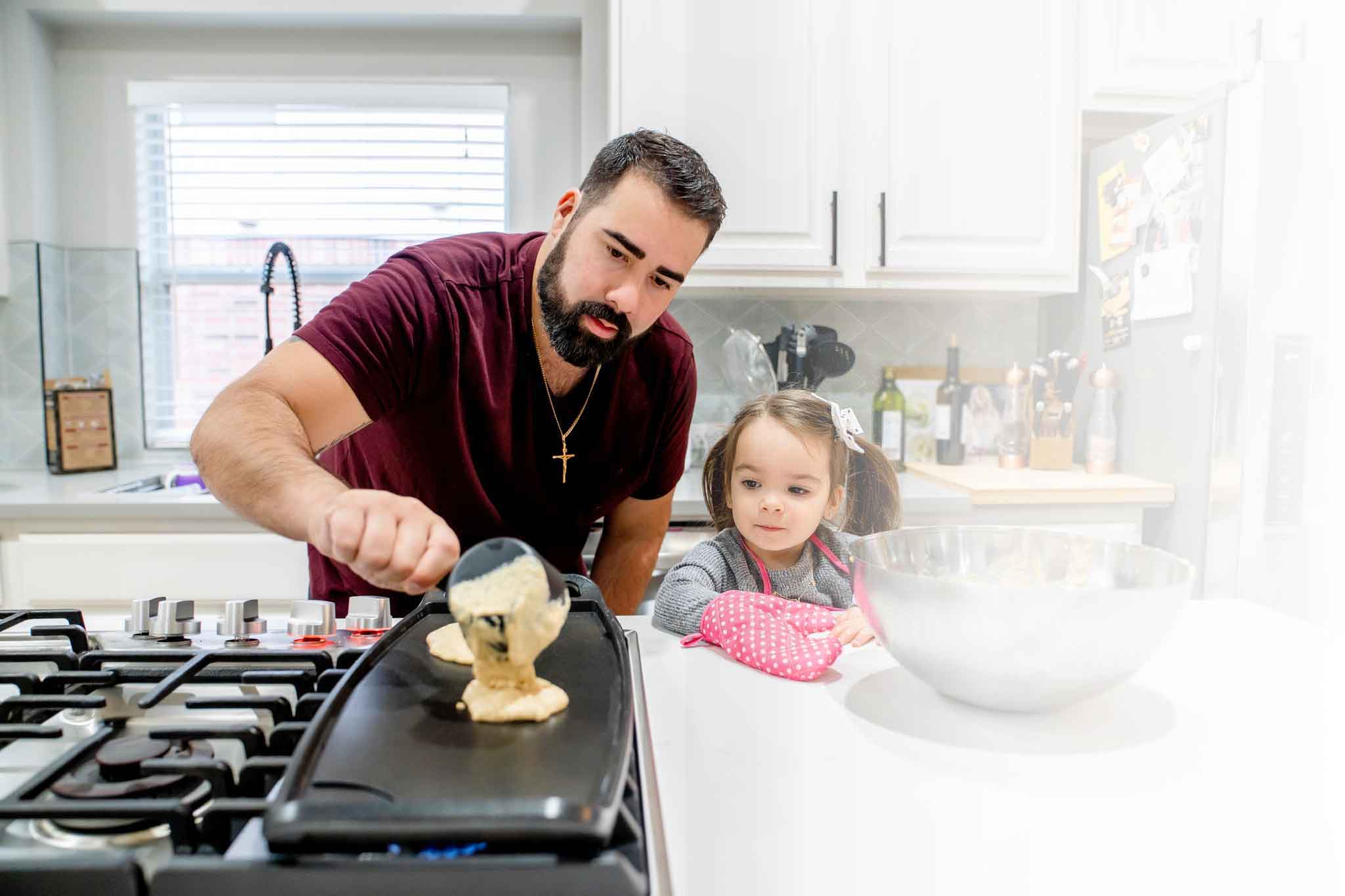 Padre haciendo panqueques con su hija en la cocina